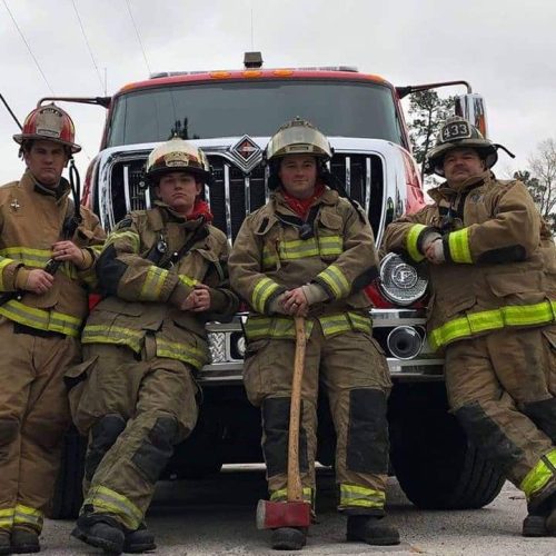 Four firemen from the C shift, in front of their fire truck.